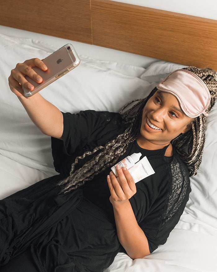 how to take your own passport photos - woman in bed taking selfie